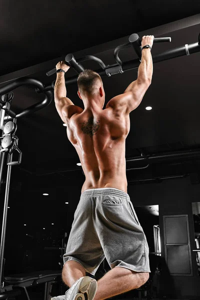 Bodybuilder gör pull-ups. Muskulös man i gymmet. Förberedelser för tävlingar, funktionell träning. Idrottaren får sin form. — Stockfoto