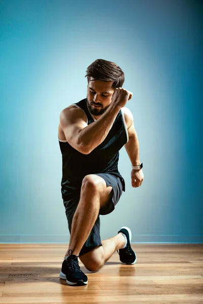 一个男人在灰色背景的体育馆里做功能性运动。健美概念、体形、体形阳性、复制空间 — 图库照片