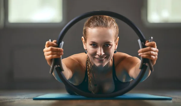 Entrenador de fitness muestra ejercicios con un expansor de anillo, por la mañana en la sala de fitness. Espacio de copia, motivador de fitness . —  Fotos de Stock