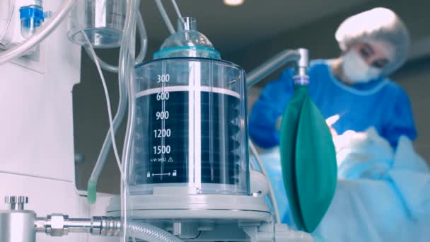 Il funzionamento del pistone del ventilatore, sullo sfondo di un medico che si prende cura di una sala da ballo in coma. Paziente in reparto per un apparecchio per la ventilazione a freddo in polmonite. Reparto con il paziente — Video Stock