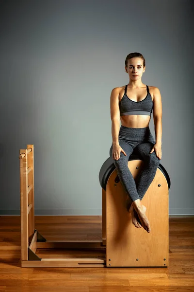 Pilates trainer exercises on a pilates barrel. Body training, perfect body shape and posture correction opporno motor apparatus. Copy space. — Stock Photo, Image