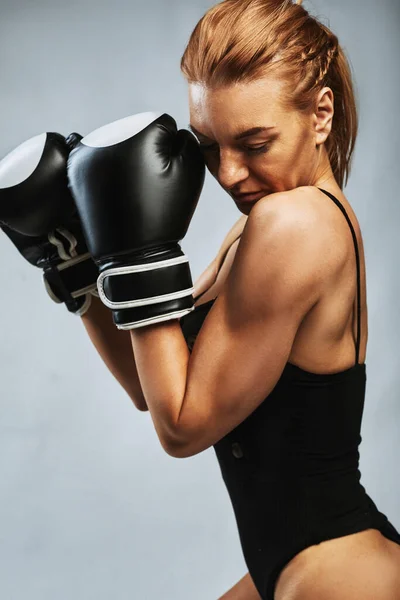 Sexy chica boxeador con atlética hermosa figura en traje de baño negro y guantes de boxeo sobre un fondo gris. Desafíate — Foto de Stock