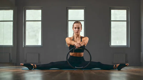 エレガントな体操教師反転手はストレッチボディとピラティスリング上の床や足で体をサポートする灰色の壁の背景スタジオで柔らかさを開発. — ストック写真