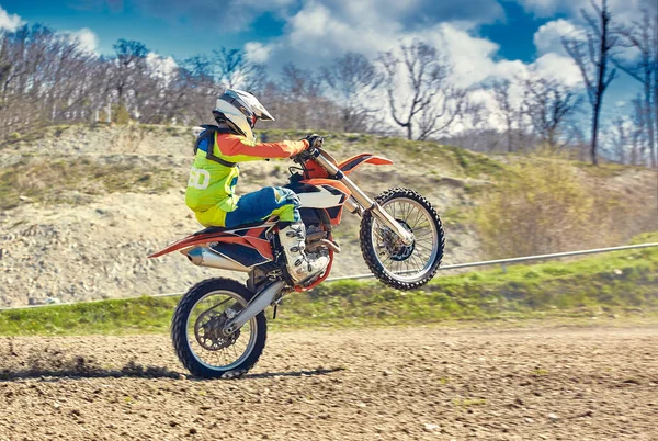 Motocross, en ryttare står på bakhjulet på en cykel, Rider på bakhjulet. Extrem, industriell, motorcykel terrängkörning för extrema. — Stockfoto
