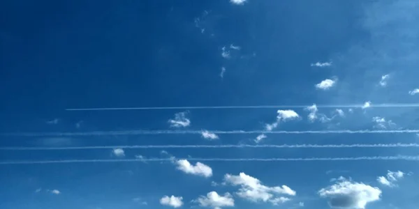 Ślad z samolotu w powietrzu. Cztery samoloty śladowe. Chmury nieba. Abstrakcyjny rozmyty niebieski gradient wiosennego nieba. — Zdjęcie stockowe