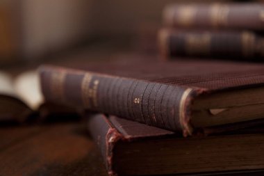 Eski kitaplar rustik ahşap masa üzerinde. Kitap yığını. Arka plan bulanık. Rustik, kahverengi ve sıcak sahne.