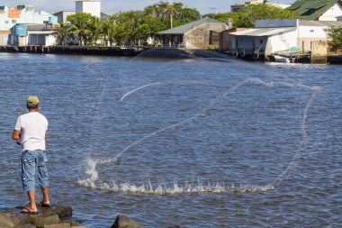 A fisherman casts his net in Mampituba river  boundary between S clipart