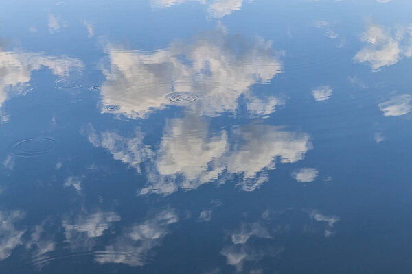 Waves in a lake reflecting sky with clouds