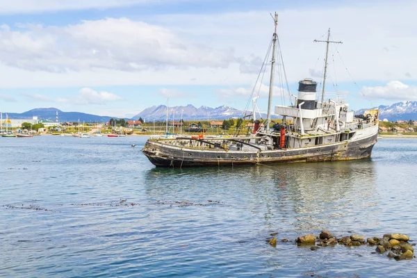 Vecchia barca nel canale Beagle con montagne e case a Ushuaia — Foto Stock