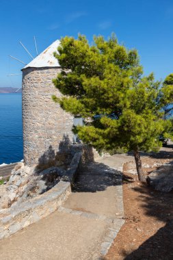 Hidra Adası 'nın arka planında okyanus olan eski rüzgar değirmeni
