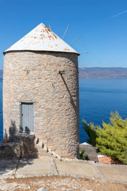 Hidra Adası 'nın arka planında okyanus olan eski rüzgar değirmeni