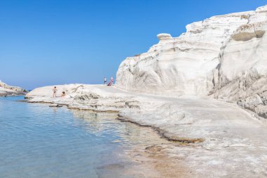 Sarakiniko sahilindeki beyaz kayalıkların keyfini çıkaran insanlar.