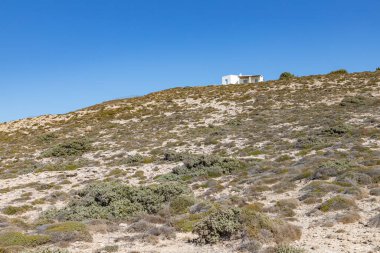 Mytakas sahilindeki küçük ev, kayalar ve bitki örtüsü, Milos, Yunanistan