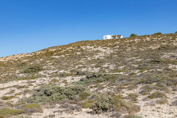 Mytakas sahilindeki küçük ev, kayalar ve bitki örtüsü, Milos, Yunanistan