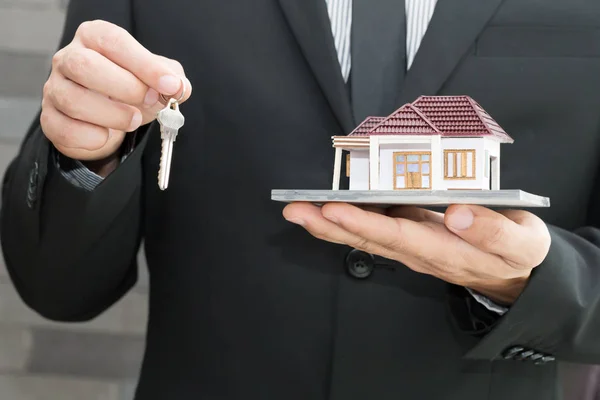 Businessman holding home model. Loan and real estate concept
