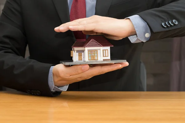 Un uomo d'affari con un modello di casa. Concetto di prestito e immobiliare — Foto Stock