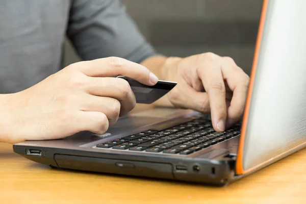 Mãos masculinas segurando cartão de crédito e usando laptop — Fotografia de Stock
