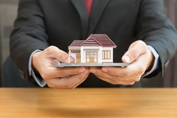 Businessman holding home model. Loan and real estate concept