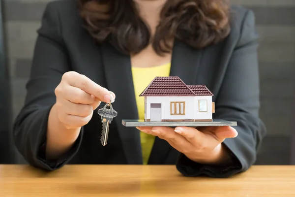 Empresária segurando modelo em casa com as chaves da casa. Conceito de empréstimo e imobiliário — Fotografia de Stock