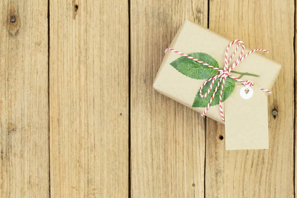 Gift box wrapped in recycled paper on wood background — Stock Photo, Image