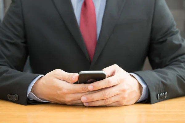 Empresário usando smartphone móvel na mesa de madeira — Fotografia de Stock