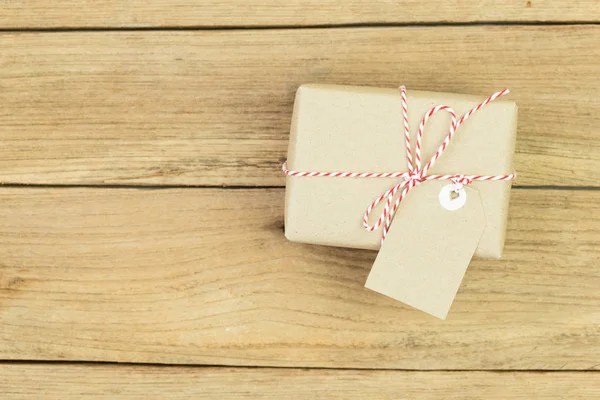 Gift box wrapped in recycled paper on wood background — Stock Photo, Image