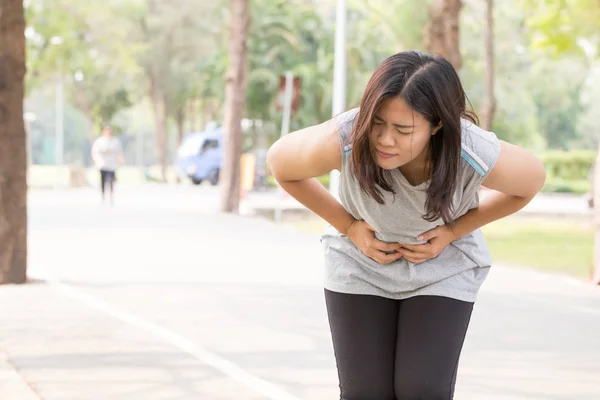 Mulher asiática dor de estômago enquanto corre no parque — Fotografia de Stock