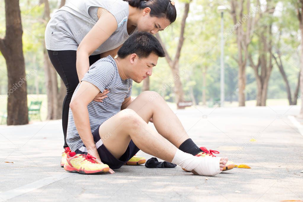 Sports injury. Man with sprained ankle and getting help from woman