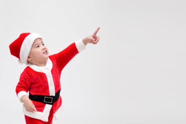 Noel Baba kostümü giymiş Asyalı bebek Noel Baba beyaz arka planda izole edilmiş, mutlu ve gülümseyen insanları işaret ediyor ve gülüyor.