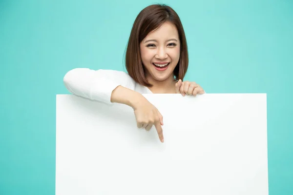 Sourire heureux asiatique femme debout derrière Gros blanc affiche et pointant doigt vers le bas — Photo