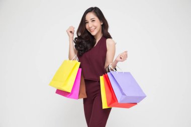 Kırmızı elbiseli alışveriş torbaları izole tutan mutlu genç bir kadın portresi beyaz arka plan, yıl sonu satış üzerinden veya yıl satış promosyon Tersanemiz Alışverişkoliğin kavramı, Asya kadın modeli için orta