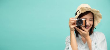 Genç Asyalı fotoğrafçı fotoğraf çekiyor. Yeşil arka planda izole edilmiş, fotokopi alanı olan ve elinde eski bir retro kamera olan model kadın turist.