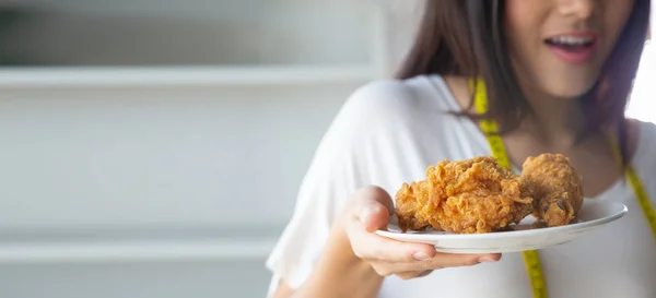 Young Asian woman holding fried chicken on plate, Junk food and weight loss concept — Stock Photo, Image