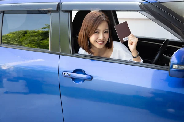 Mujer asiática feliz sosteniendo libro de pasaportes y sentado en coche, Alquilar un coche de extranjero para el concepto de viajero turístico — Foto de Stock