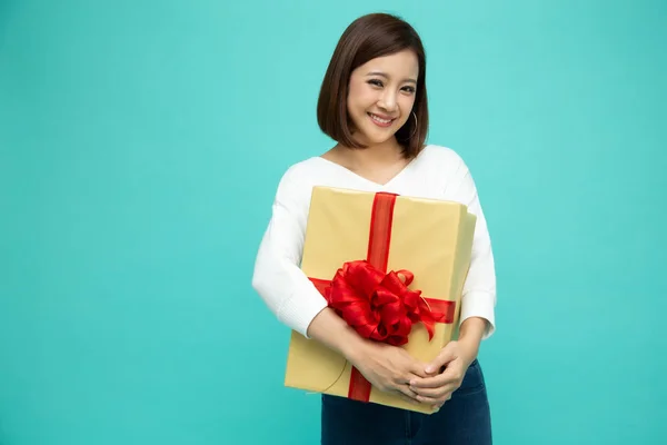 明るい緑の背景に隔離された金のギフトボックスと幸せな美しいアジアの女性の笑顔。恋人からの贈り物を受け、恋に10代の女の子。新年、クリスマスとバレンタインデーのコンセプト — ストック写真