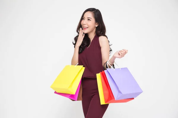 Portrait of a happy young women in red dress holding shopping bags isolated over white background, Year end sale or mid year sale promo cleence for Shopaholic concept, Asian female model — Stok Foto