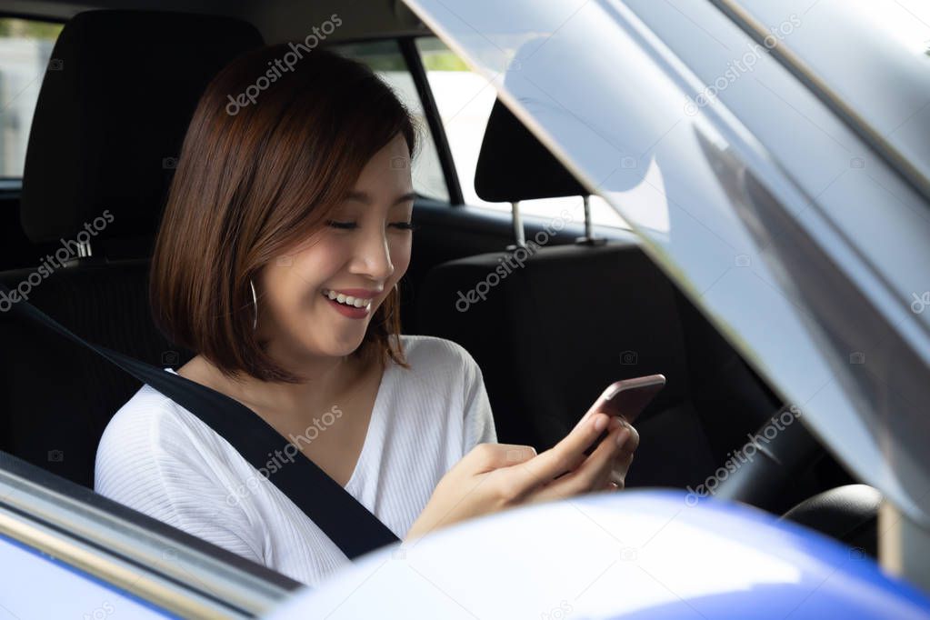 Asian woman using phone and sending a message behind the wheel, Female driving a car with using navigation or application on smartphone, Smart technology concept