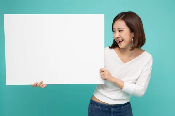 Молодая привлекательная азиатка показывает и держит чистую белую доску . — стоковое фото