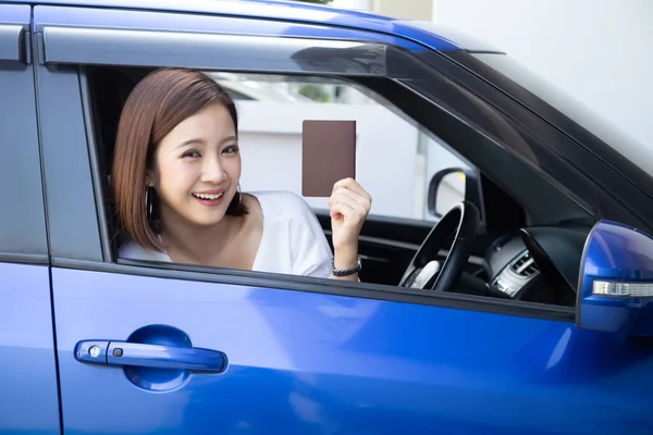 Mujer asiática con pasaporte sentado en el asiento del conductor en el coche — Foto de Stock