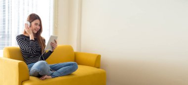 Kulaklık takan Asyalı genç kız okul kapanırken ekran tabletine bakarak internetten dil öğreniyor ve sosyal mesafeye ihtiyaç duyuyor. Evde eğitim ve öğrenim