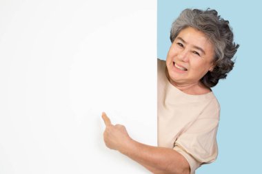 Gülümseyen Asyalı son sınıf öğrencisi bir şeyi işaret ediyor.