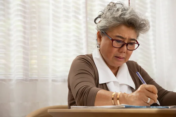 Asiatisk Senior Kvinde Seriøs Nedskrivning Breve Stykke Papir Arbejde Hjemmefra - Stock-foto