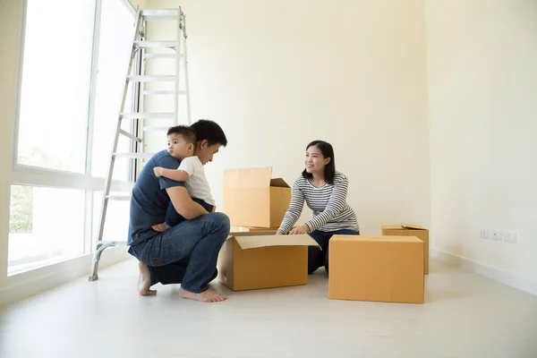 Happy Asian family with cardboard boxes in new house at moving day, Real estate and home concept