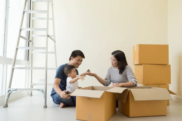 Happy Asian family with cardboard boxes in new house at moving day, Real estate and home concept