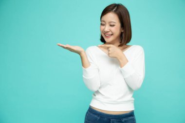 Genç zarif Asyalı kadın gülümseyen ve boş fotokopi alanına sunan yeşil arka planda izole edilmiş Tayland modeli