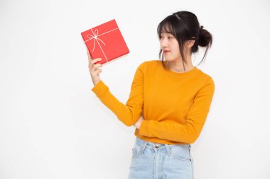 Beyaz arka planda kırmızı hediye kutusu olan mutlu, güzel Asyalı kadın gülümsemesi. Aşık ergen kızlar, sevgililerinden hediyeler alıyorlar. Yeni Yıl, Noel ve Sevgililer Günü konsepti