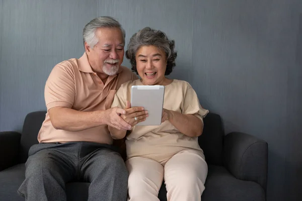 Pareja Asiática Seniors Sonriendo Mirando Misma Tableta Sofá Casa Hombre — Foto de Stock