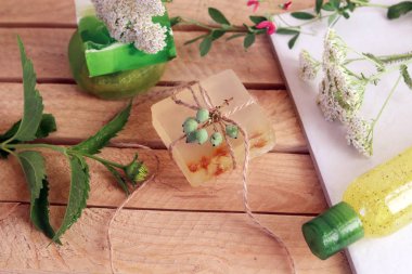 Ahşap bir masada doğal sabun, bitki ve çilek, spa prosedürleri, vücut bakımı, sağlıklı yaşam tarzı