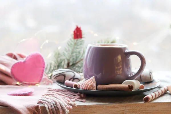 Cup of coffee with meringues and dessert on a plate, Christmas decor, hearts on the windowsill, home comfort concept, winter