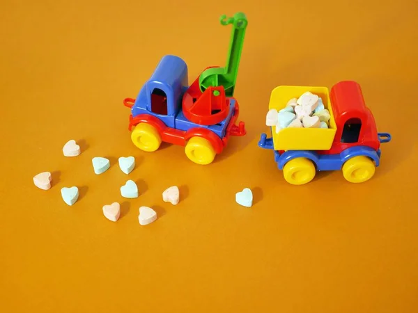 Toy car with a load of vitamin tablets in the form of a heart on a bright background, the concept of health or congratulation on Valentine\'s Day